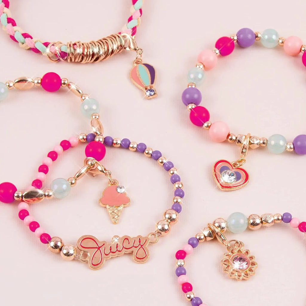 Colorful beaded bracelets with charms on a pink background