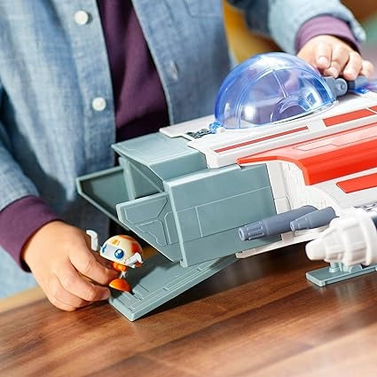 Child playing with a toy spaceship and figures on a wooden table