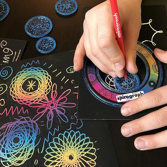 Person using a Spirograph kit to create colorful designs on black paper.