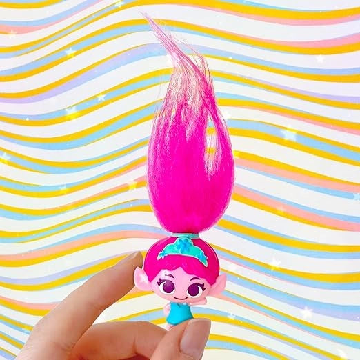 Toy figure with pink hair held against a colorful striped background