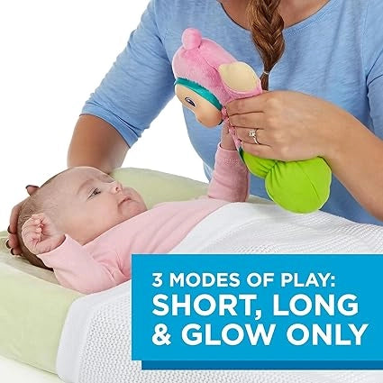 Baby lying on a changing table with a colorful toy held by an adult, text indicating '3 Modes of Play: Short, Long & Glow Only'.