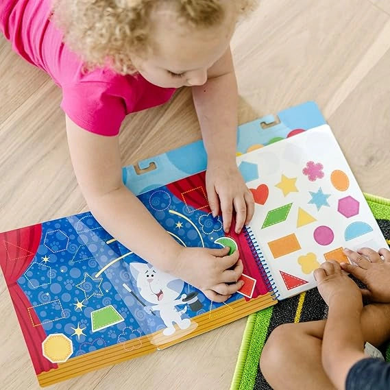 Child playing with a colorful educational book on a wooden floor