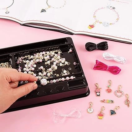 Jewelry-making kit with beads and charms on a pink surface