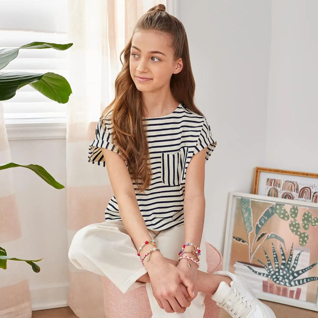 Young girl sitting on a couch in a room with plants and artwork.