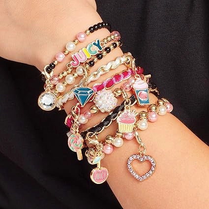 Multicolored charm bracelets on a wrist against a black background