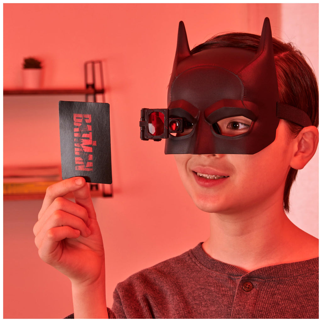 a child holding detective card of batman kit.